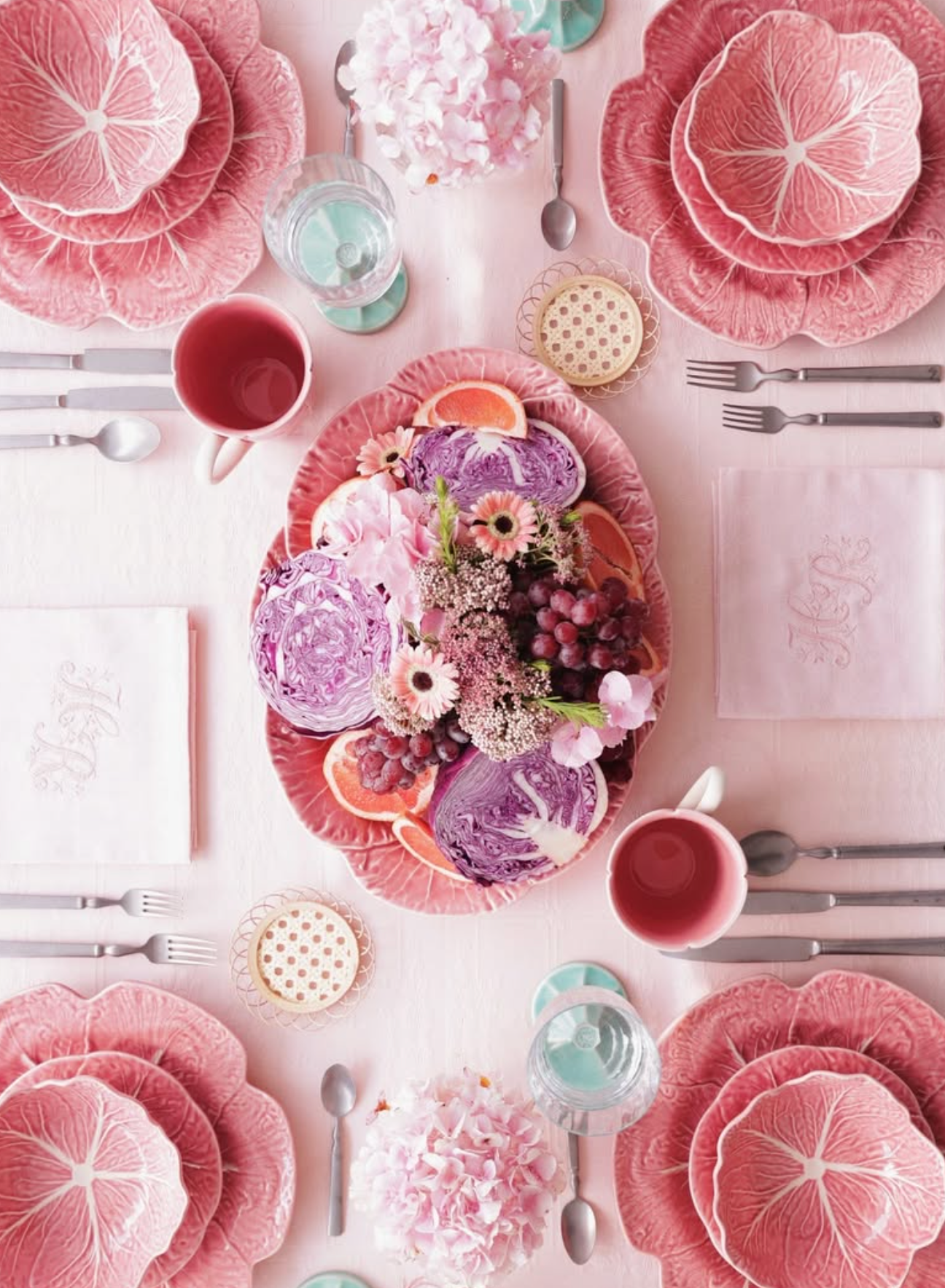 Elegant table setting with pink and purple plates, floral centerpieces, and silverware.