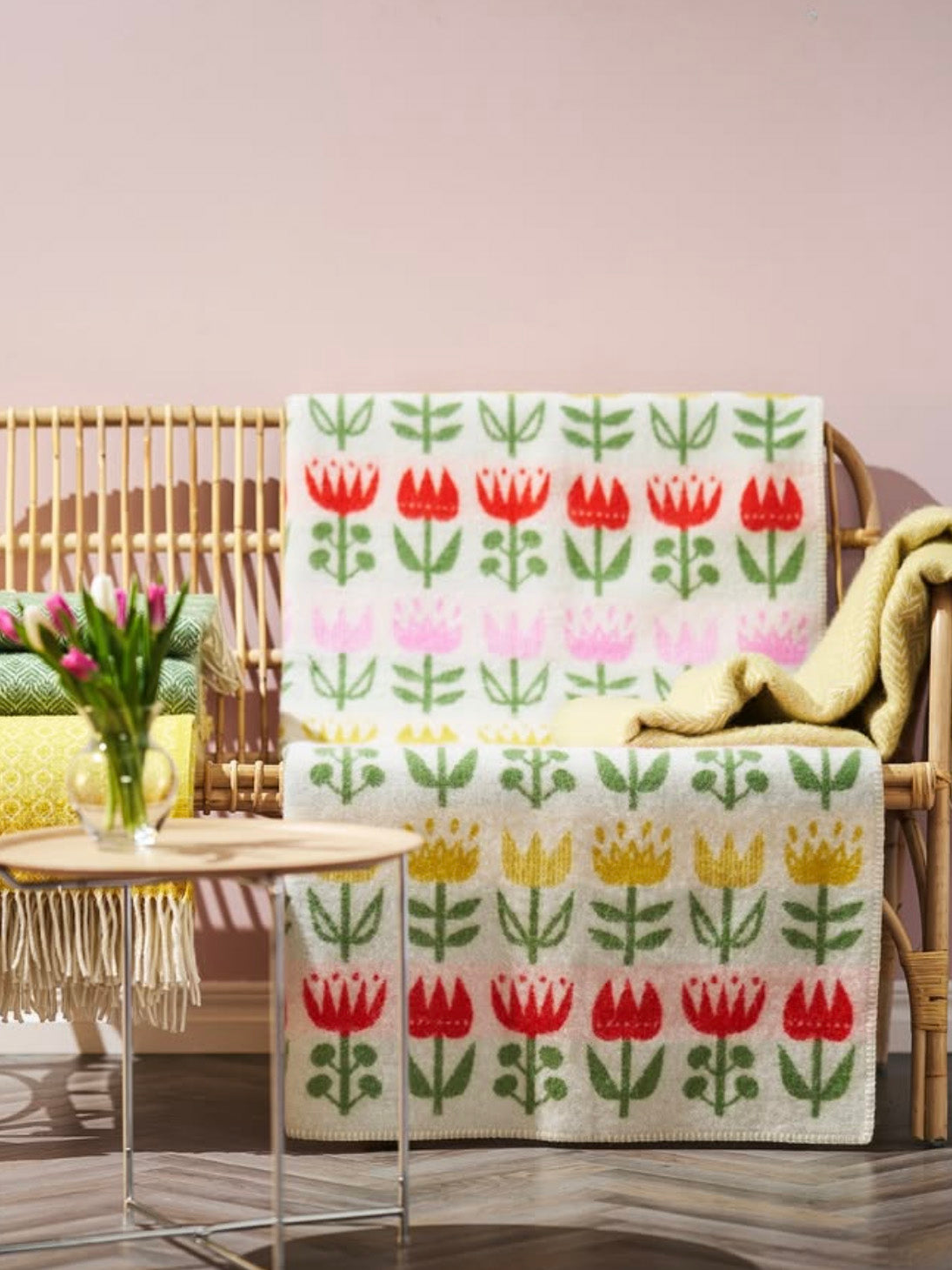 Floral-patterned blanket draped over a chair with a table and flowers in the background