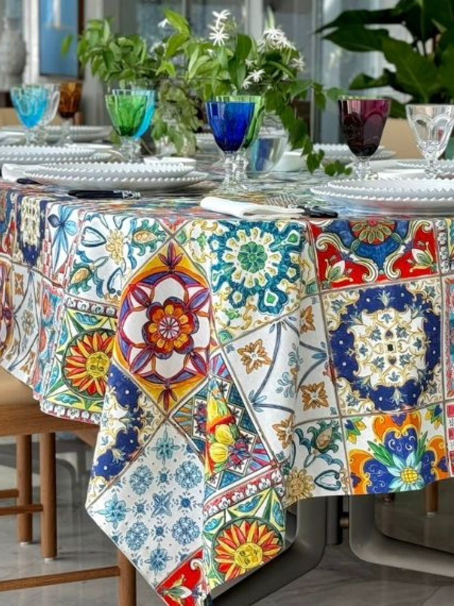 Colorful patterned tablecloth on a dining table with decorative glasses and plates.