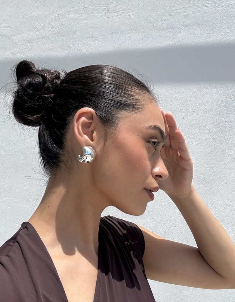 Woman with a bun and earring against a light gray background