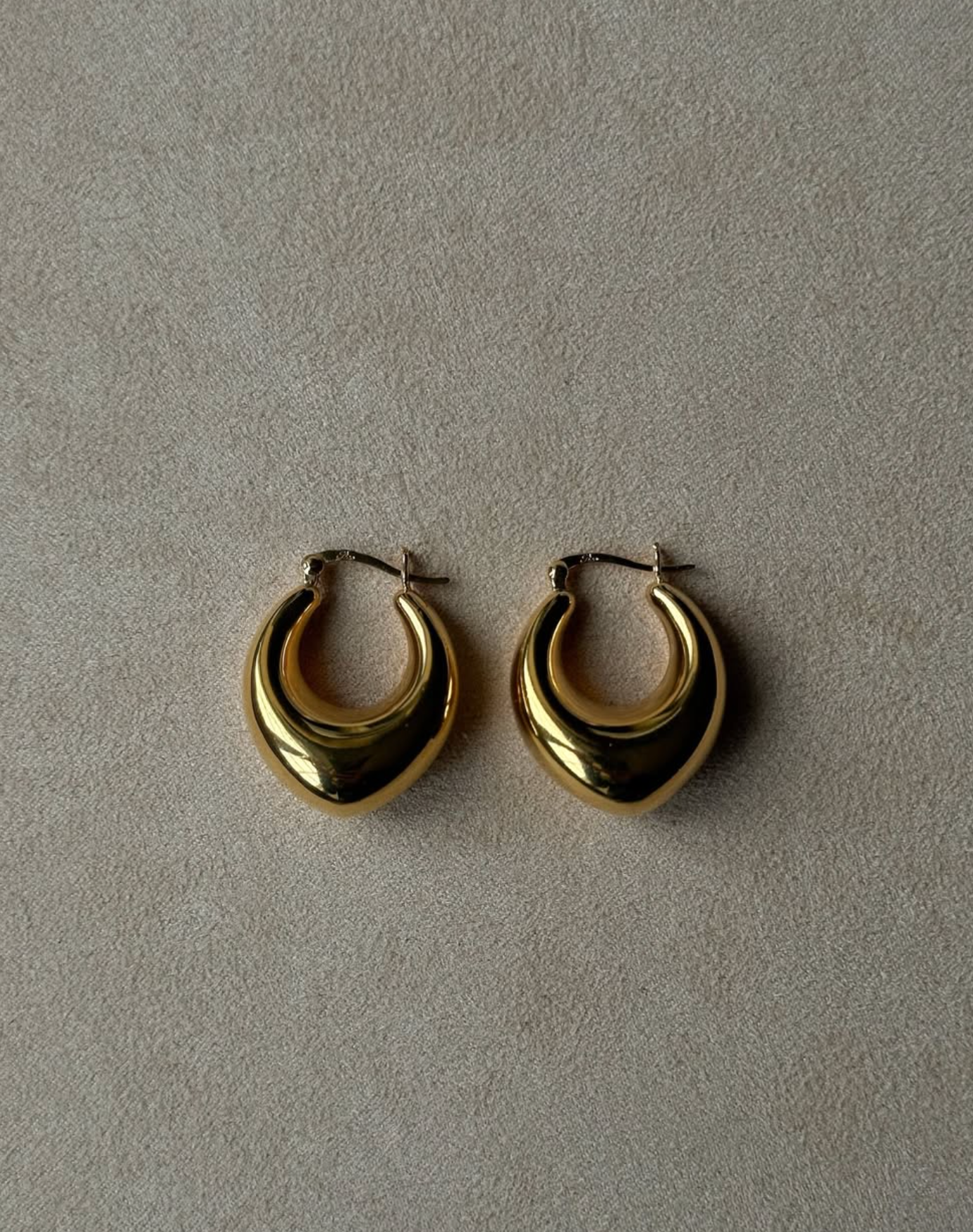 Gold hoop earrings on a gray background