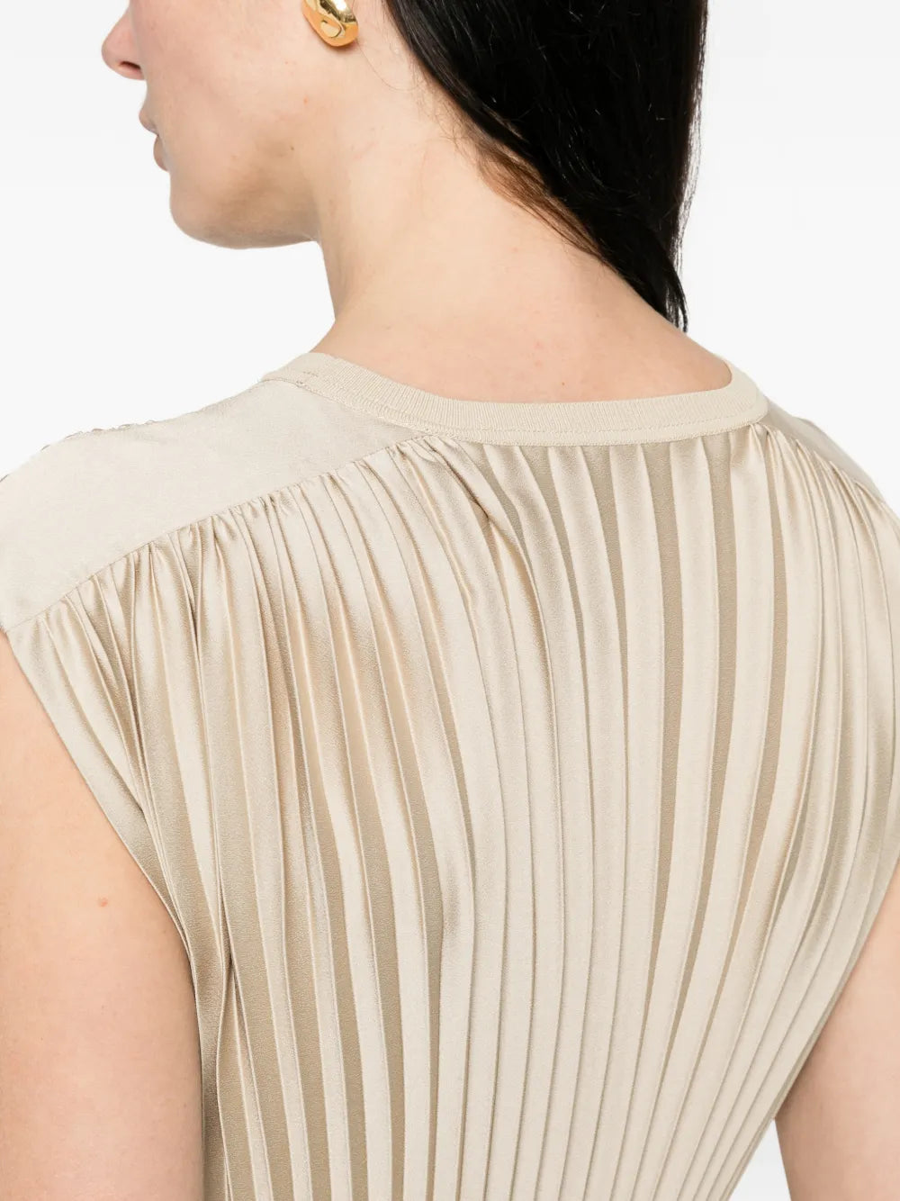 Beige pleated top worn by a person on a white background