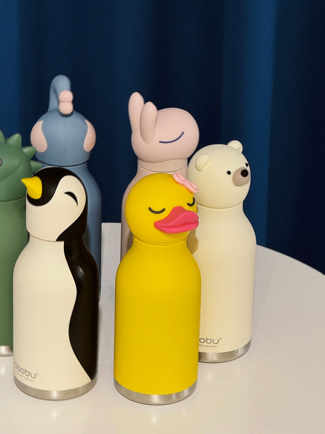 Set of colorful animal-themed water bottles on a white surface with a dark blue background