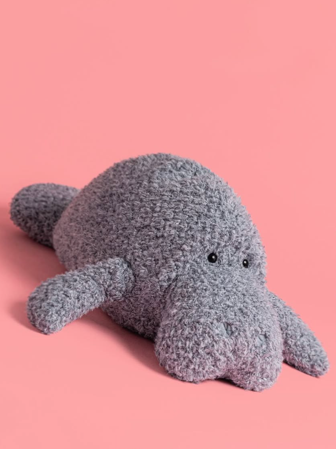 Plush toy manatee on a pink background