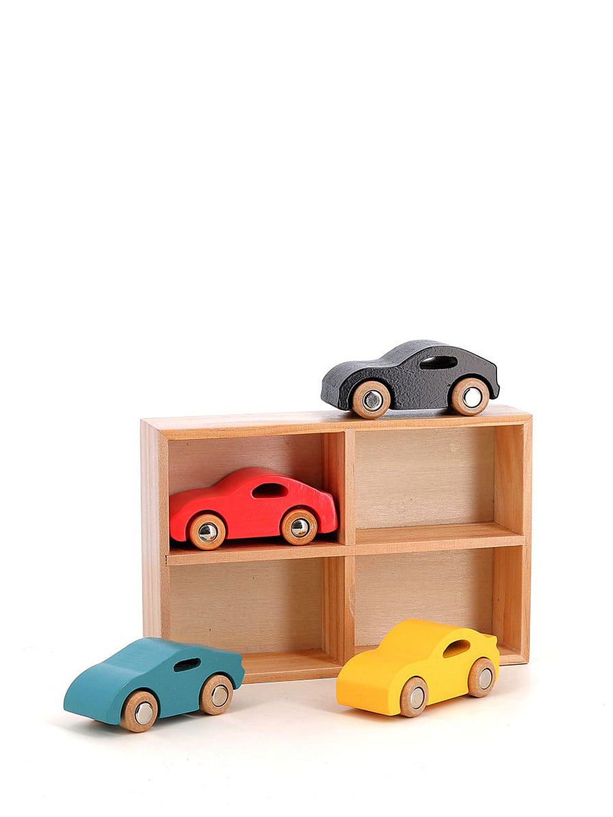 Set of colorful wooden toy cars on a wooden shelf against a white background