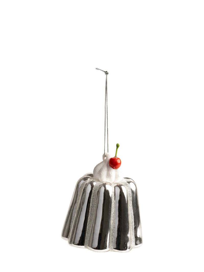A silver metallic pudding-shaped hanging ornament with white whipped cream, a small red cherry, and a thin metal hanging loop, shown on a plain white background.