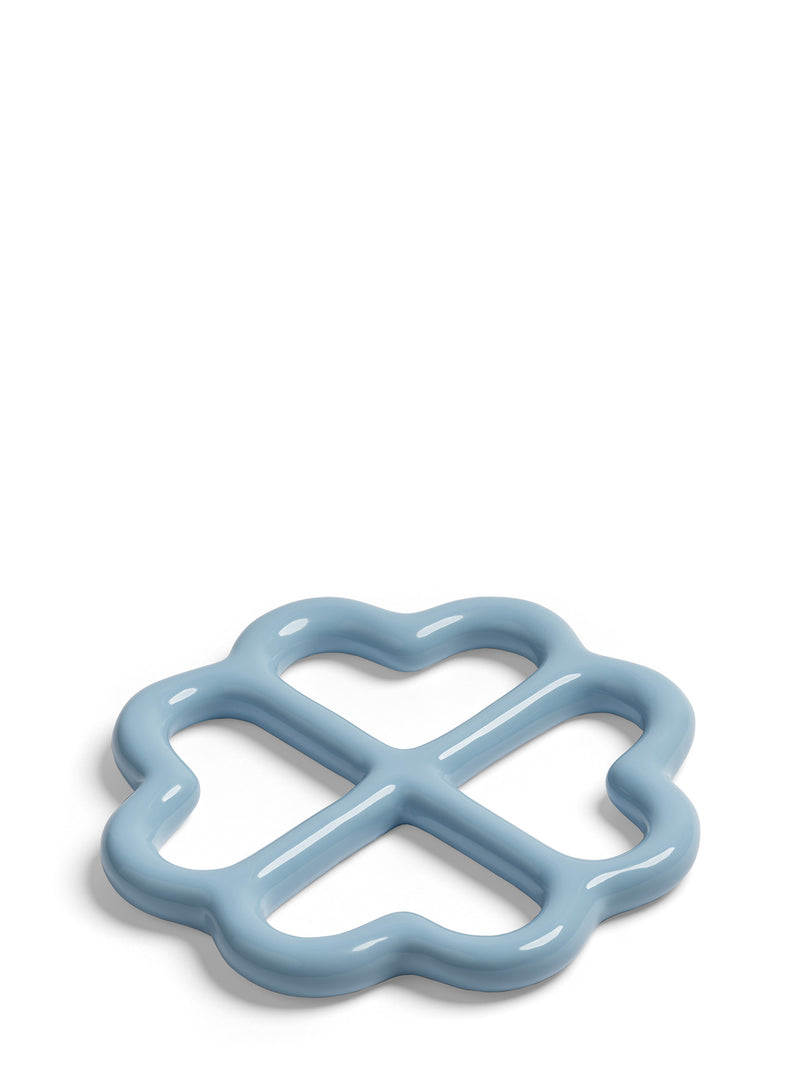 A light blue trivet ring with a wavy clover-like outline and a central cross design, shown on a clean white background.