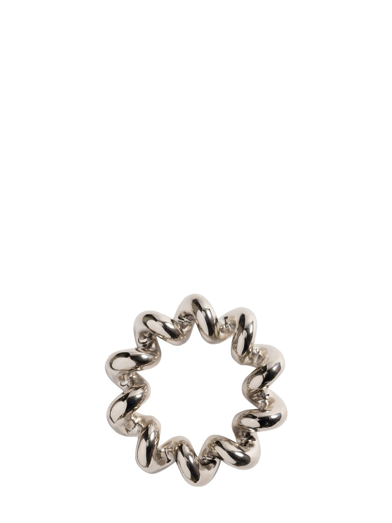 A silver metallic looking trivet with a wavy, segmented design, photographed on a solid white background.