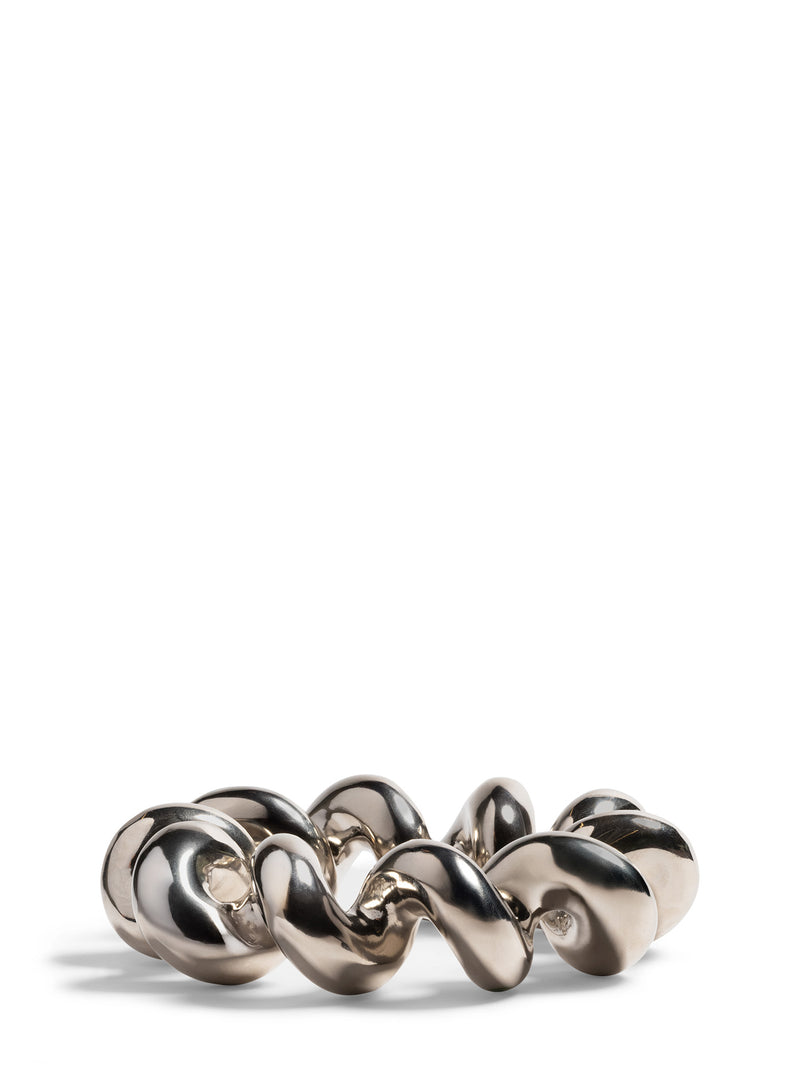 A chunky shiny trivet with metallic glaze and a wavy, organic link design, photographed on a clean white background.