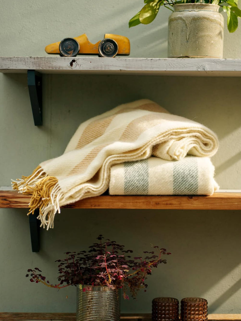 Stack of folded towels on a wooden shelf with decorative items.