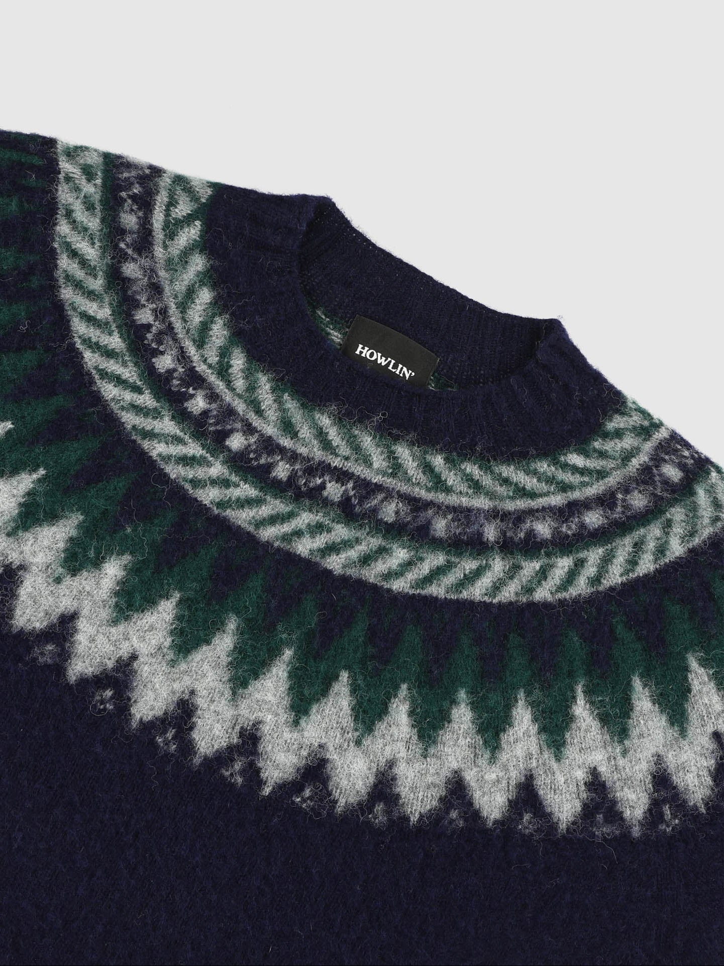 Close-up of a navy sweater with green and white pattern on a light gray background