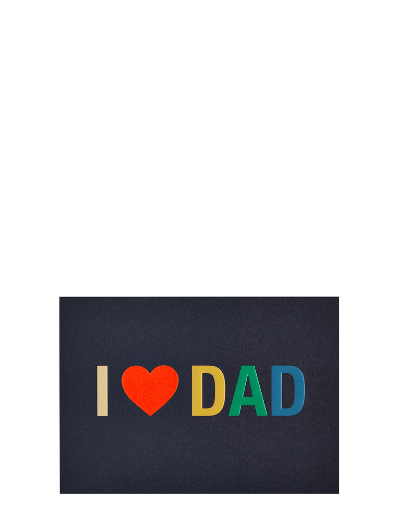 A rectangular dark charcoal greeting card with the text 'I' in beige, a red heart, and 'DAD' in yellow, green, and blue, shown on a plain white background.