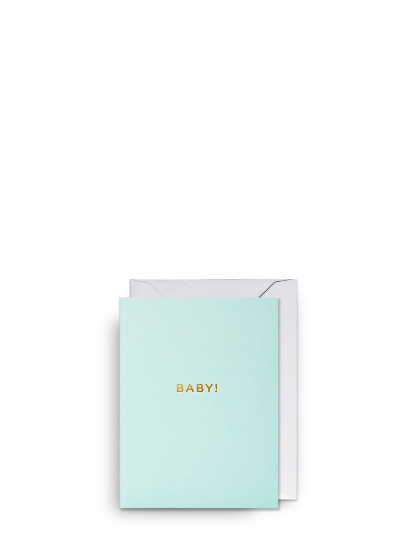 Pastel mint green greeting card with 'BABY!' in gold and a white envelope behind the card on a white background
