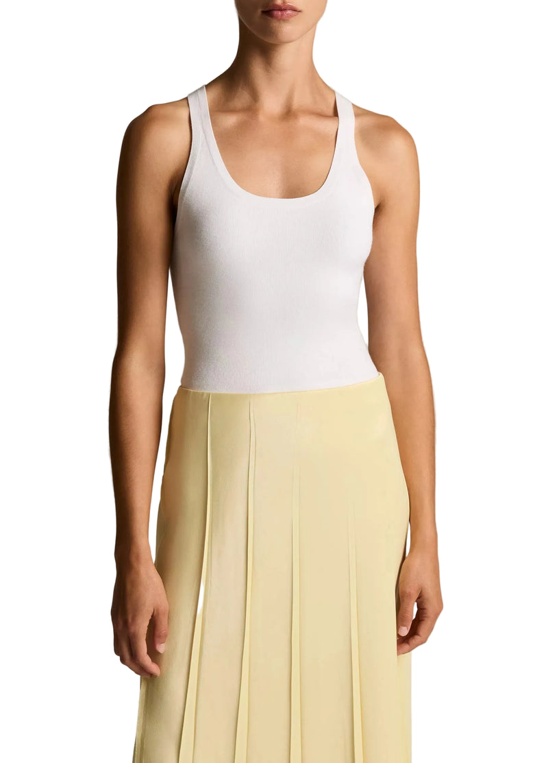 Person wearing a white tank top and yellow skirt on a plain background