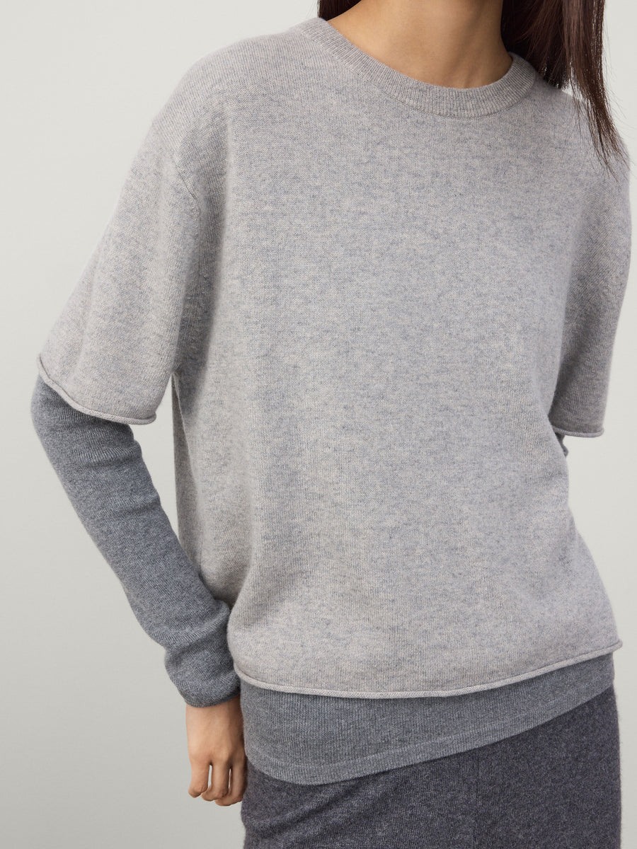 Person wearing a gray sweater against a plain background