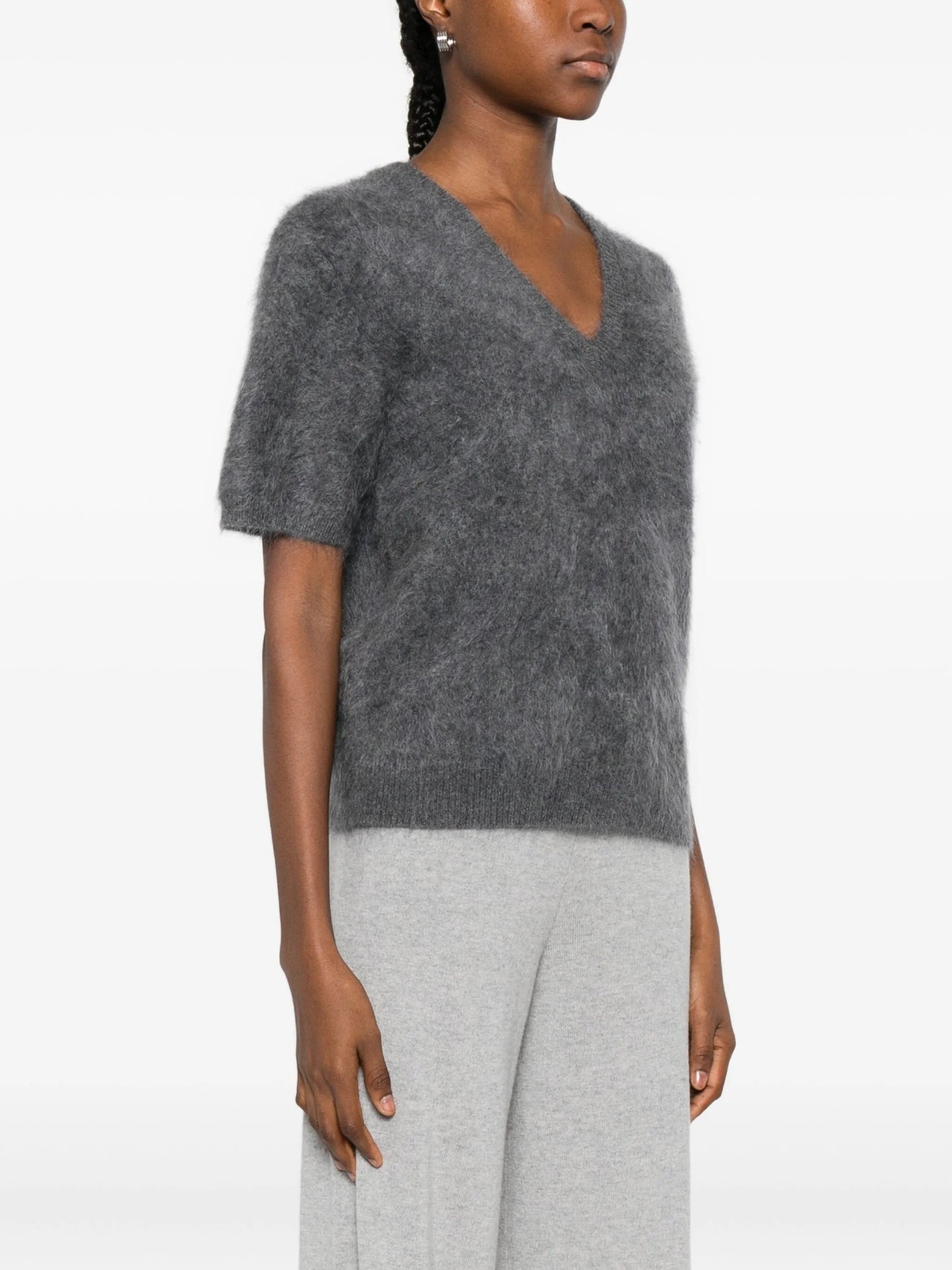 Woman wearing a grey knit top and pants on a white background