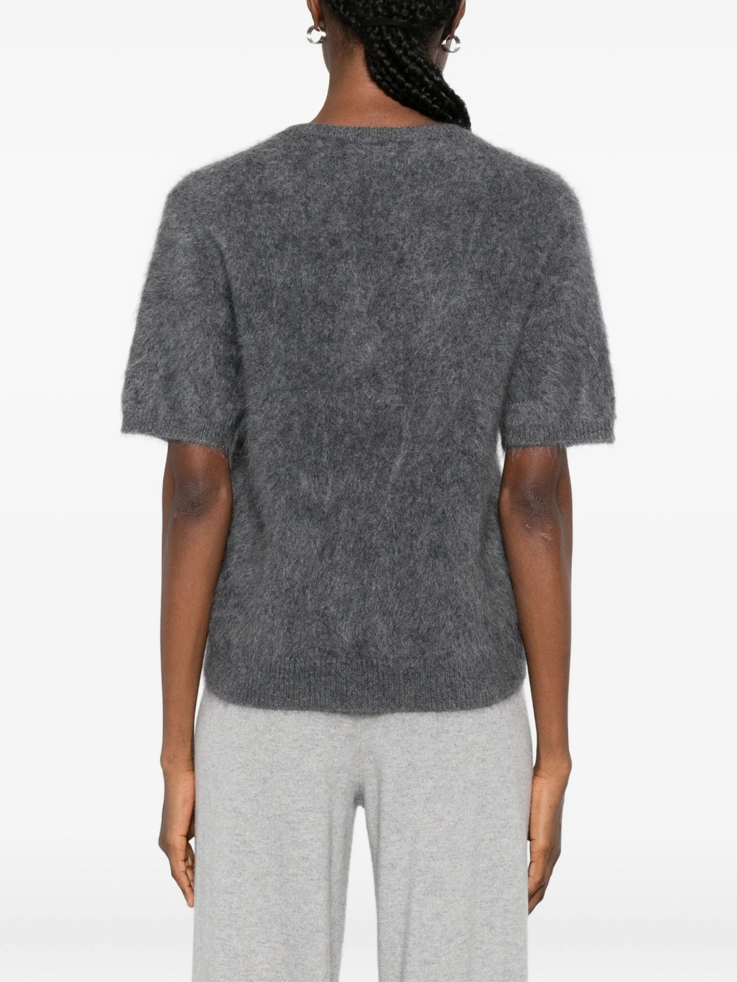 Person wearing a grey knit top and pants on a white background