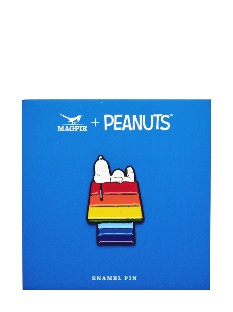 A collectable enamel pin featuring the character Snoopy from Peanuts sitting on a rainbow-colored dog house, with the Peanuts logo and 'Magpie+' branding at the top.