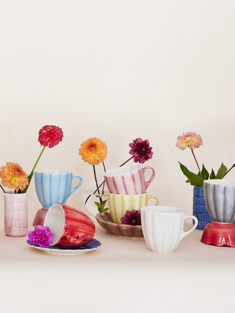 Colorful mugs with flowers on a light background