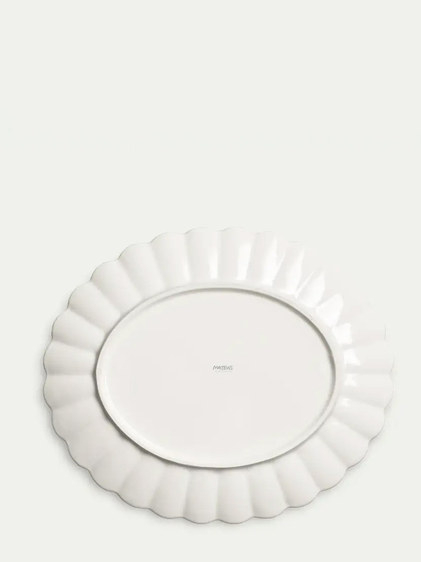 Underside of the oval large platter glazed in white, scalloped edge on a light gray background and name Mateus at the middle