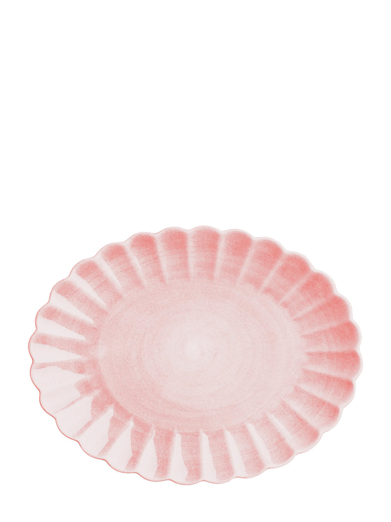 Oval shallow plate with softly scalloped edges and light pink glaze photographed from up against white backround