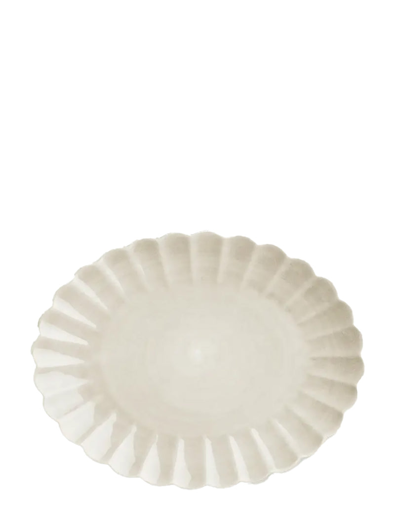 Oval off-white ceramic plate with scalloped edge on a white background