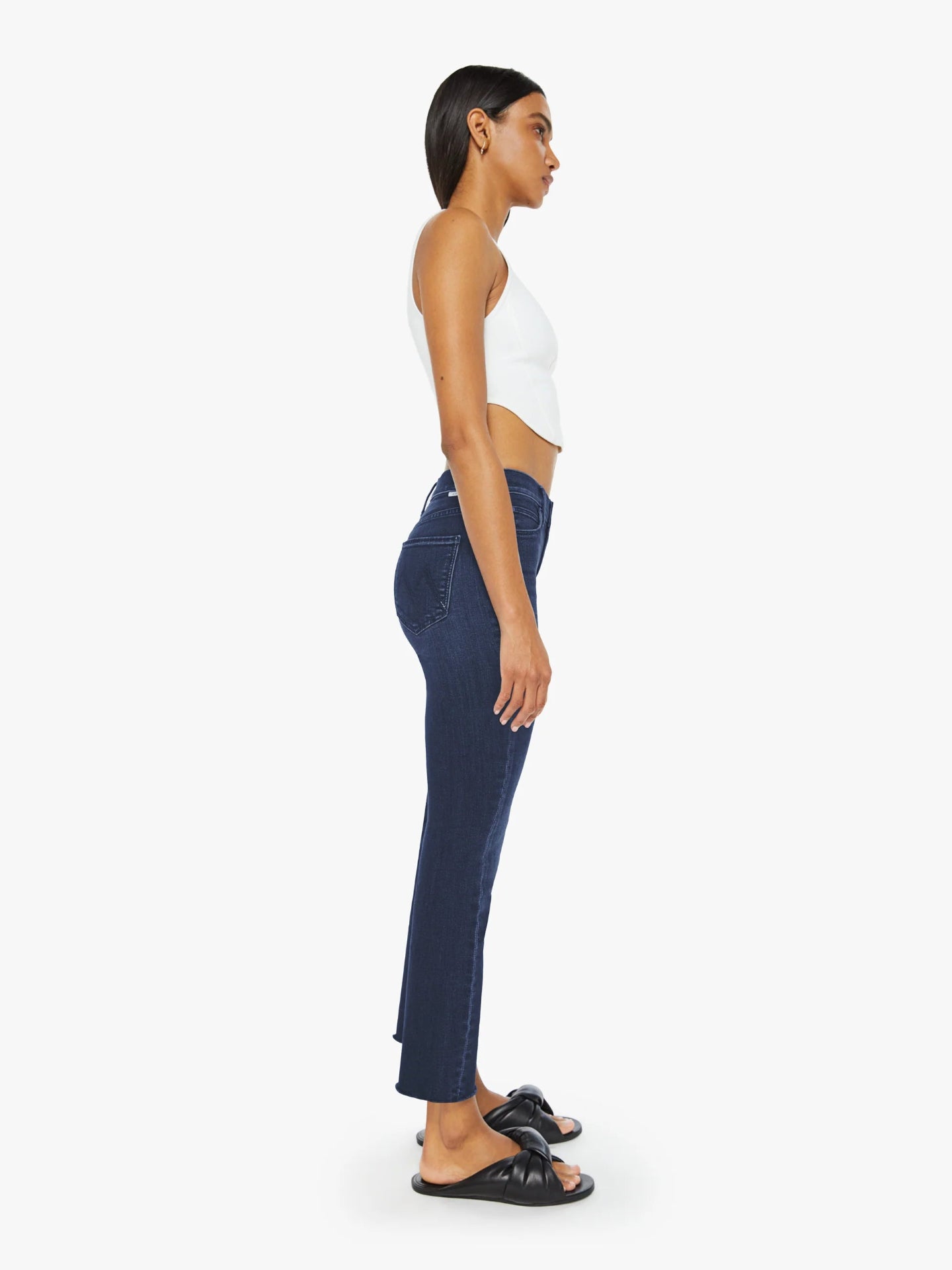 Woman wearing dark blue jeans and a white top on a white background