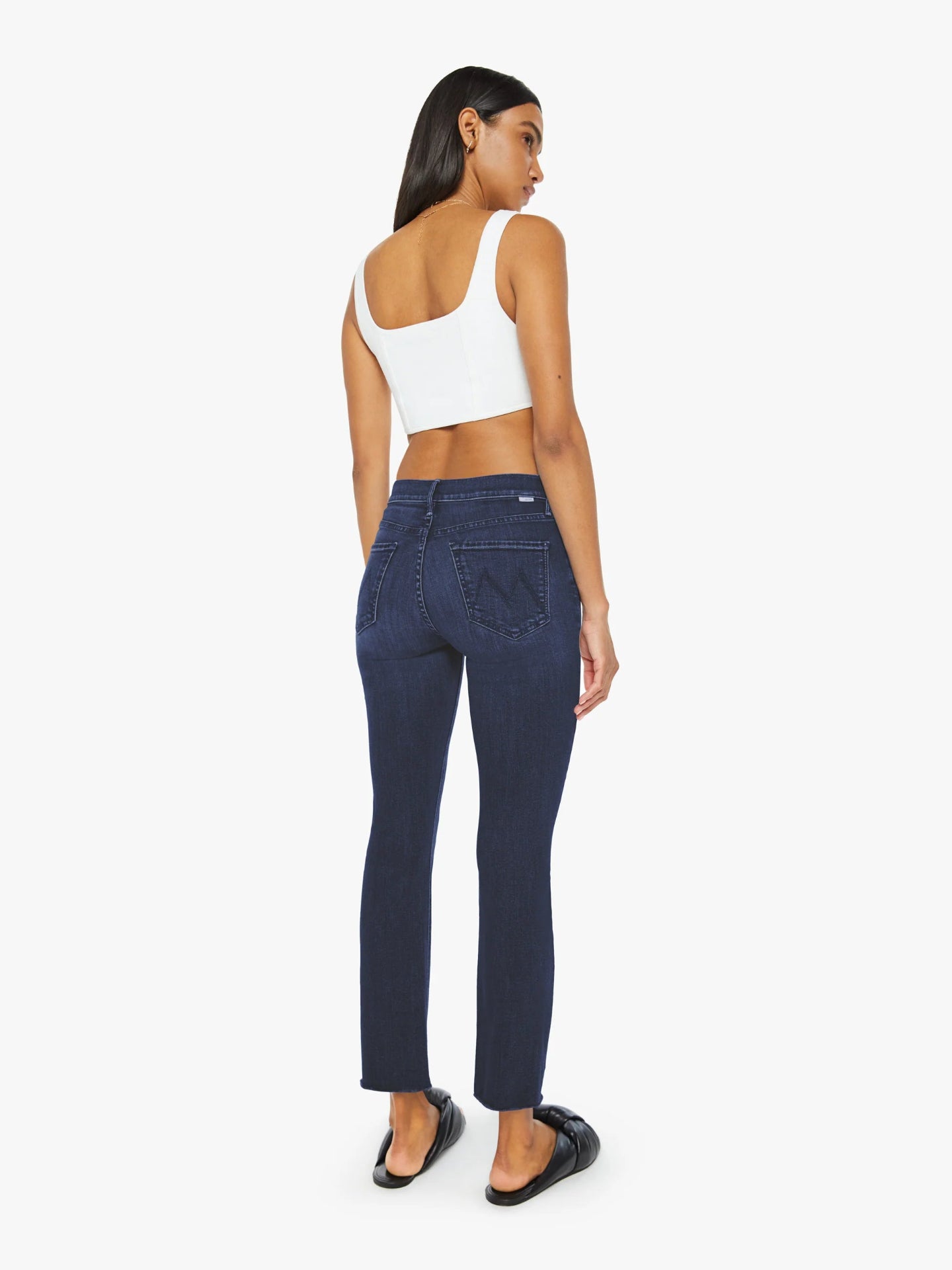 Woman wearing dark blue jeans and a white top on a white background
