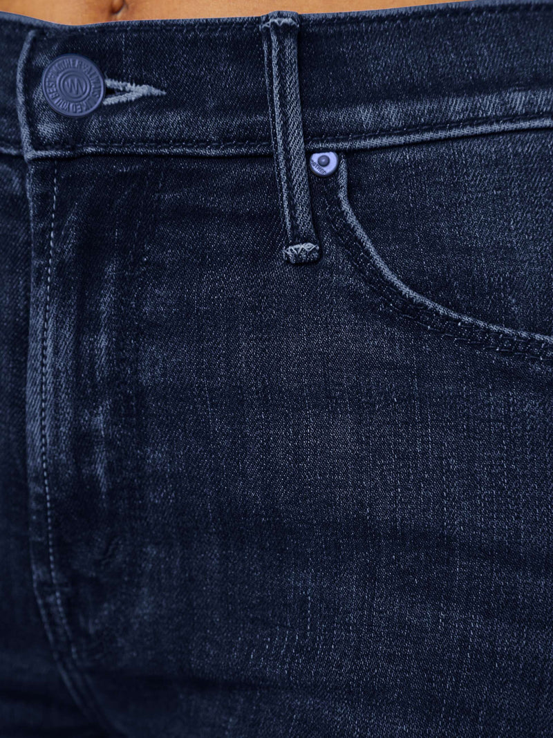 Close-up of dark blue jeans with a brand logo on the pocket.