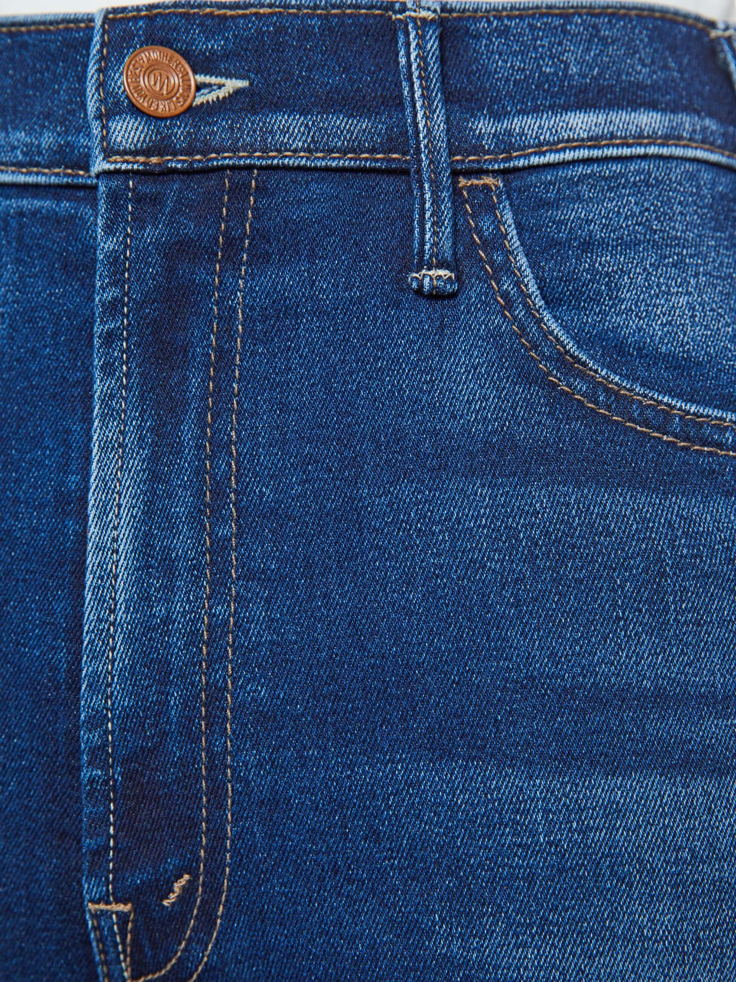 Close-up of blue denim jeans with a brand logo on the button.
