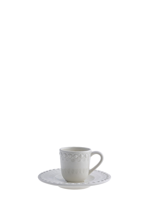 White ceramic cup and saucer with decorative patterns on a white background