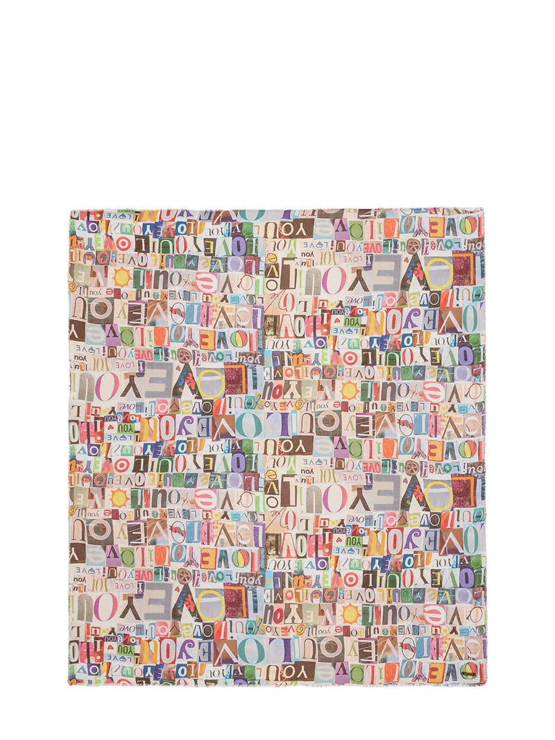 A square fabric item, likely a clutch cover or small pouch, featuring a dense multicolor collage pattern of the word 'AMERICA' in various fonts and colors on a light background.