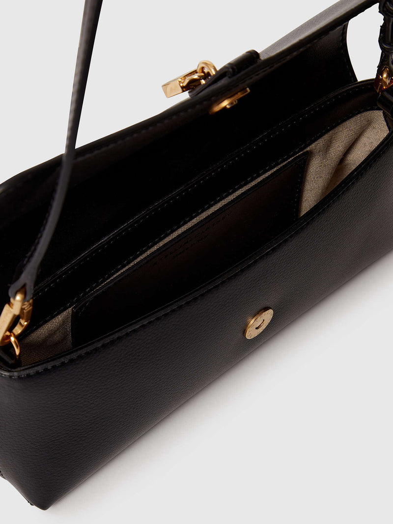 Close-up of a black leather handbag showing the interior, gold-tone hardware, and a small round gold logo button on a light gray background.
