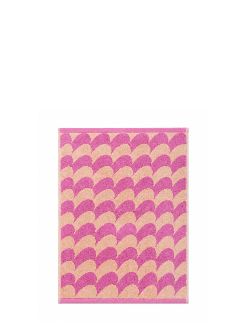 A rectangular terry cotton hand towel with a pink and pastel peach curvy mountain line or fish-scale pattern and a solid pink border, shown against a plain white background.