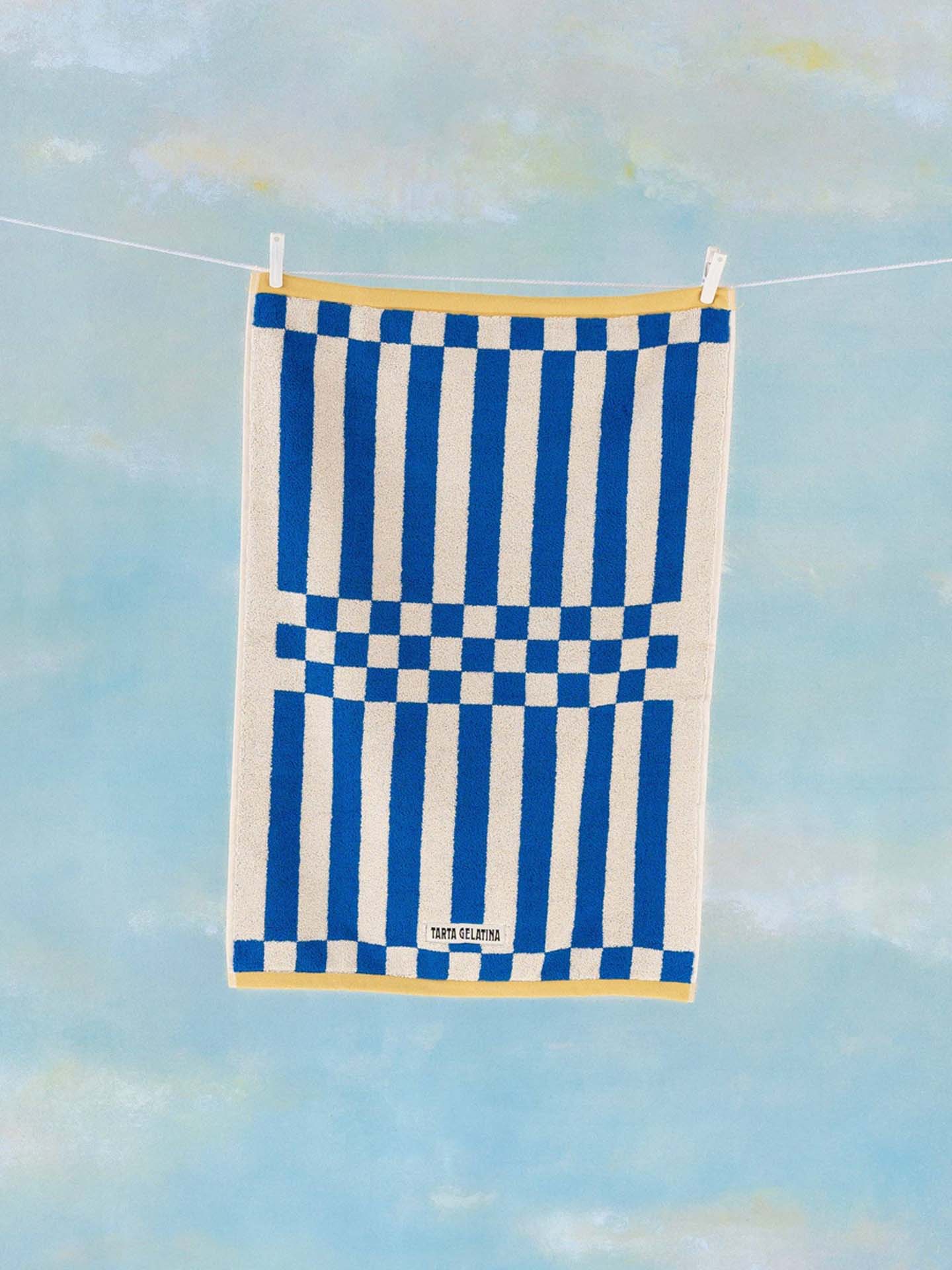 Blue and white checkered towel hanging on a line against a blue sky.