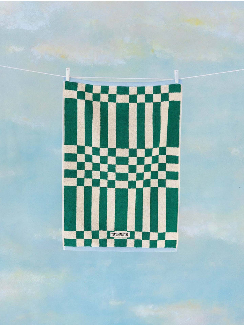 Green and white checkered towel hanging on a line against a blue sky background