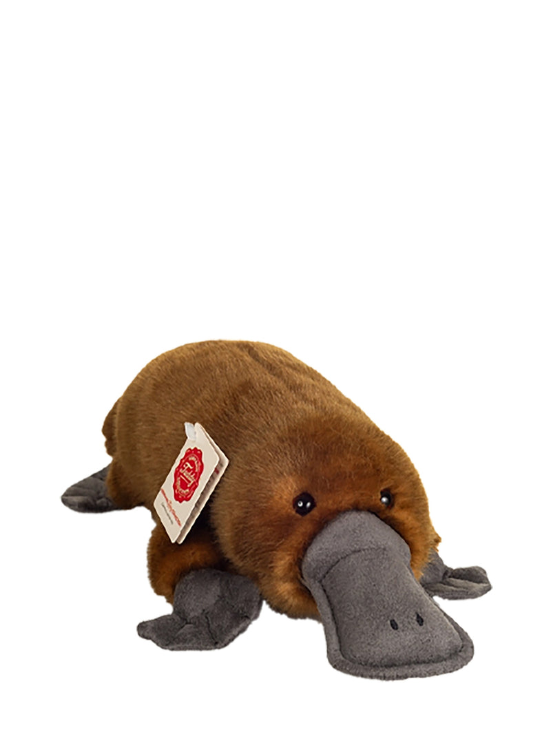 A brown plush platypus toy with a gray beak and feet, shown on a plain white background. A small paper tag is attached to its side.