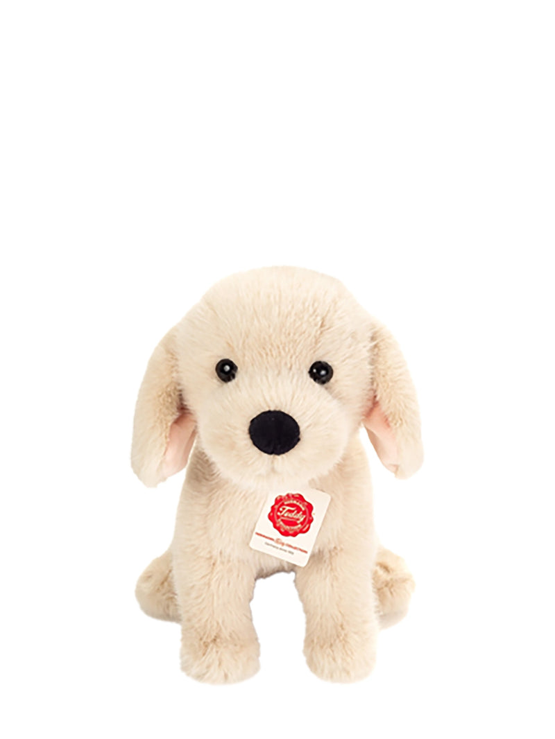 A plush puppy toy in light cream or off-white faux fur, sitting and facing forward on a plain white background. It has black plastic eyes and nose, floppy ears, and a small white hangtag with a red logo.