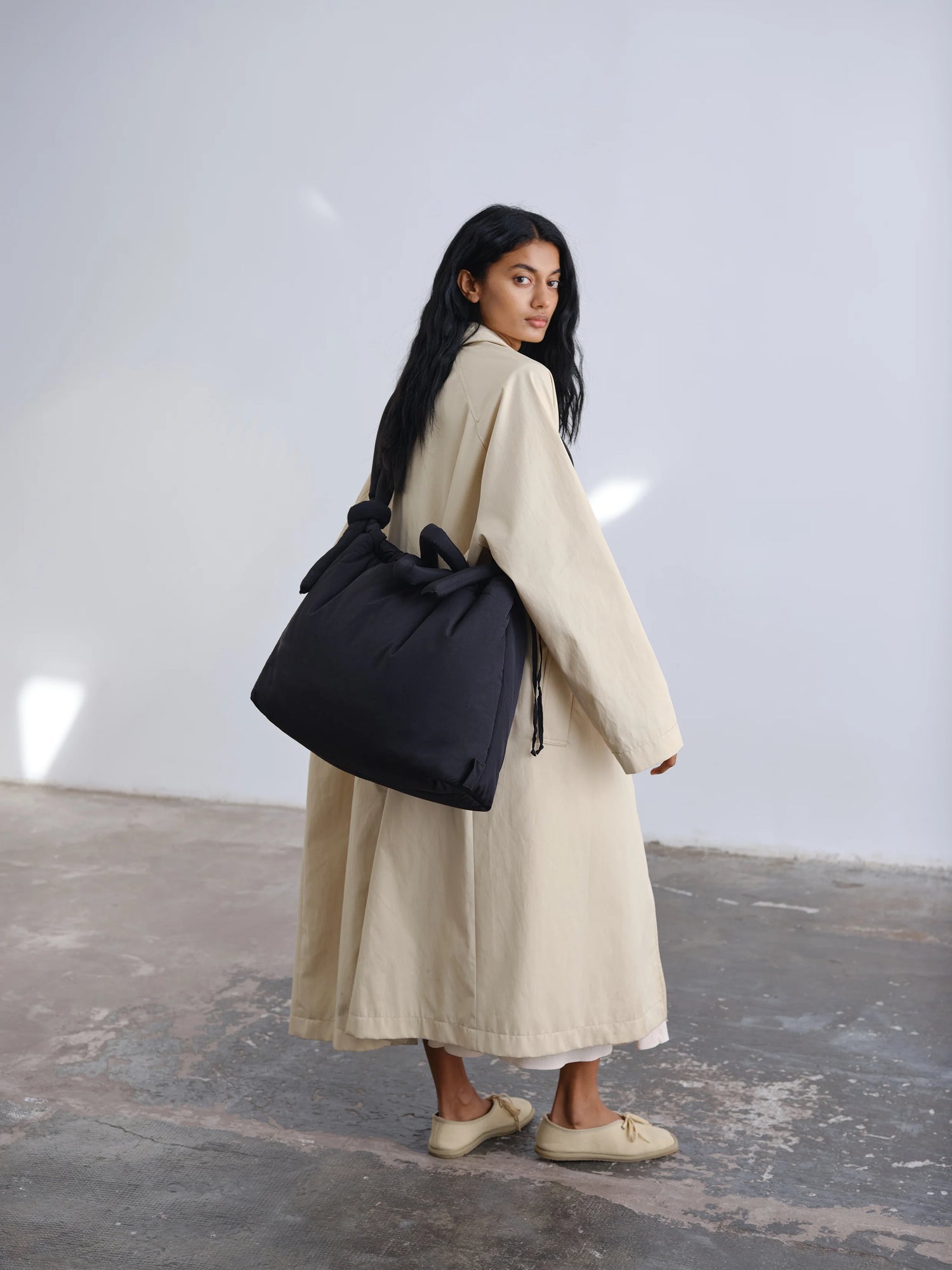 Woman holding a black bag in a minimalistic setting