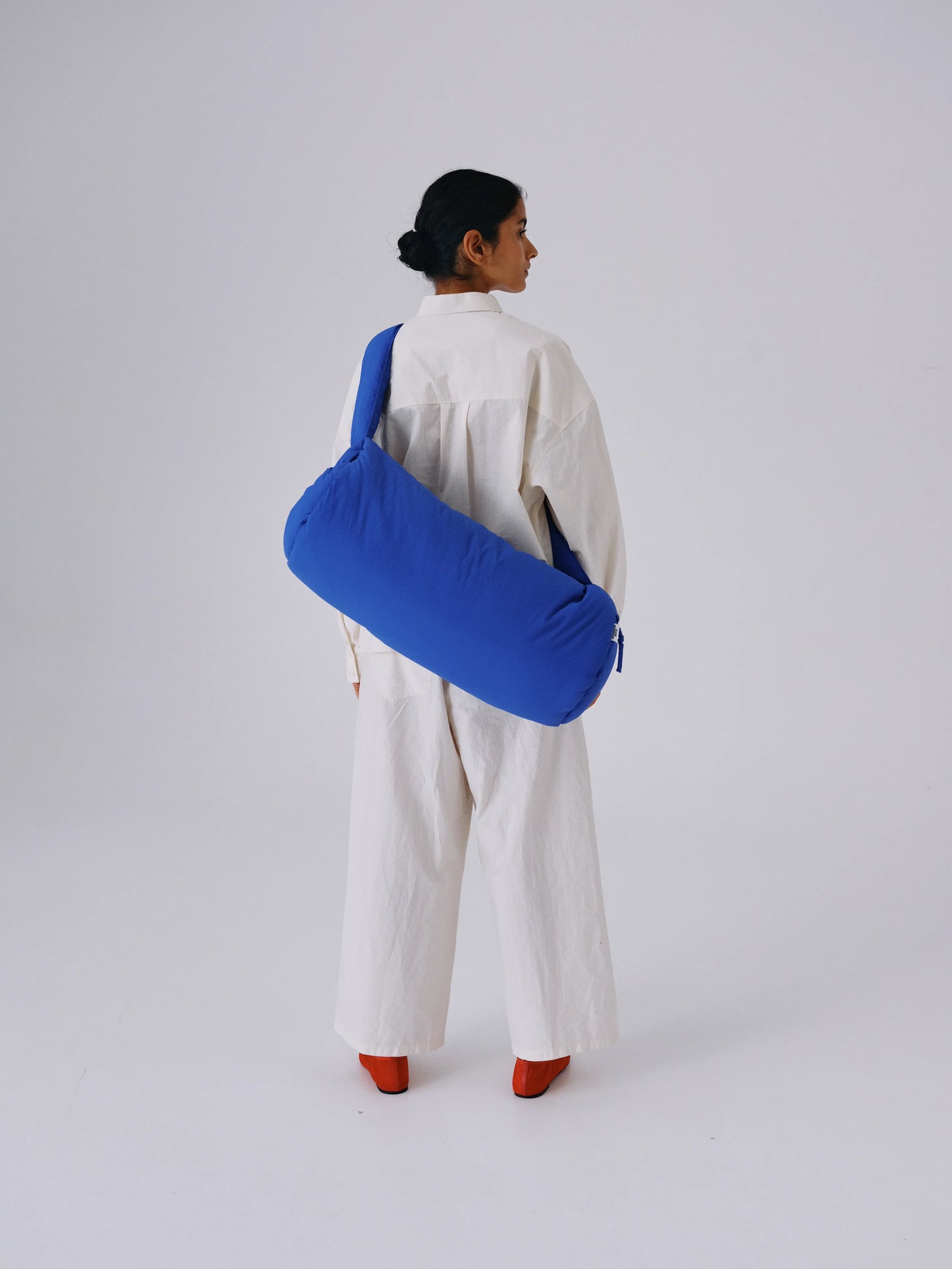 Person wearing a blue bag over one shoulder on a white background