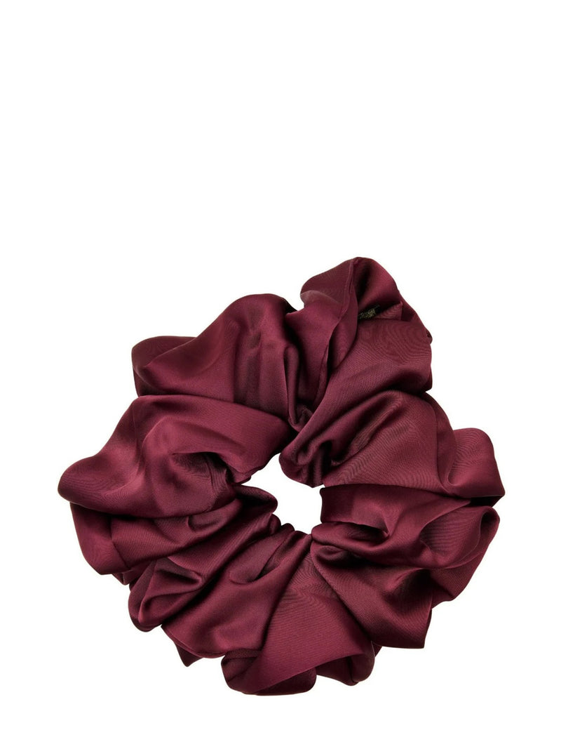 A single dark burgundy red satin hair scrunchie, photographed from above on a solid white background.