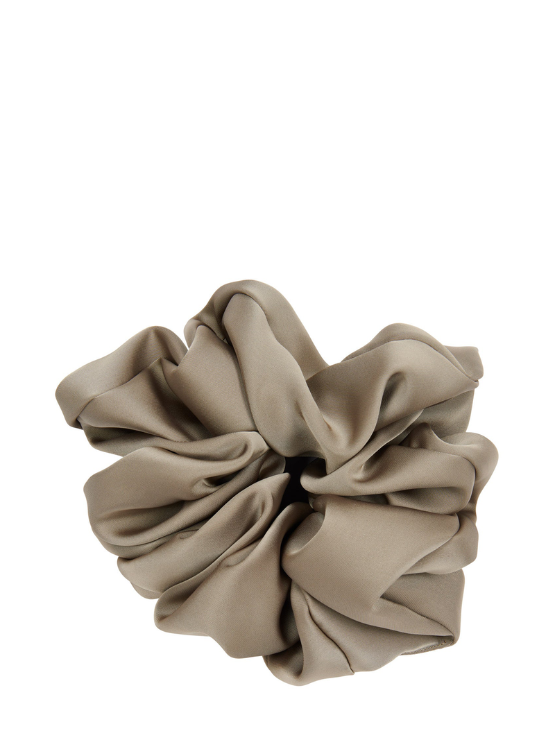 Muted light khaki beige scrunchie in multiple folds with light reflecting softly shown isolated against a white backround