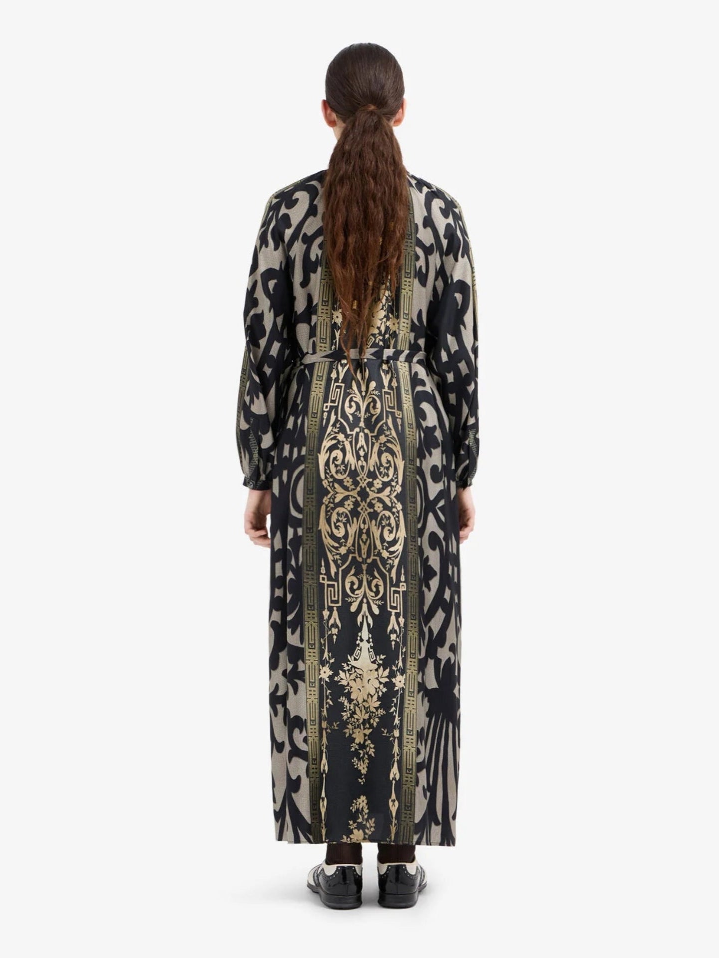 Woman wearing a long, patterned dress with a white background