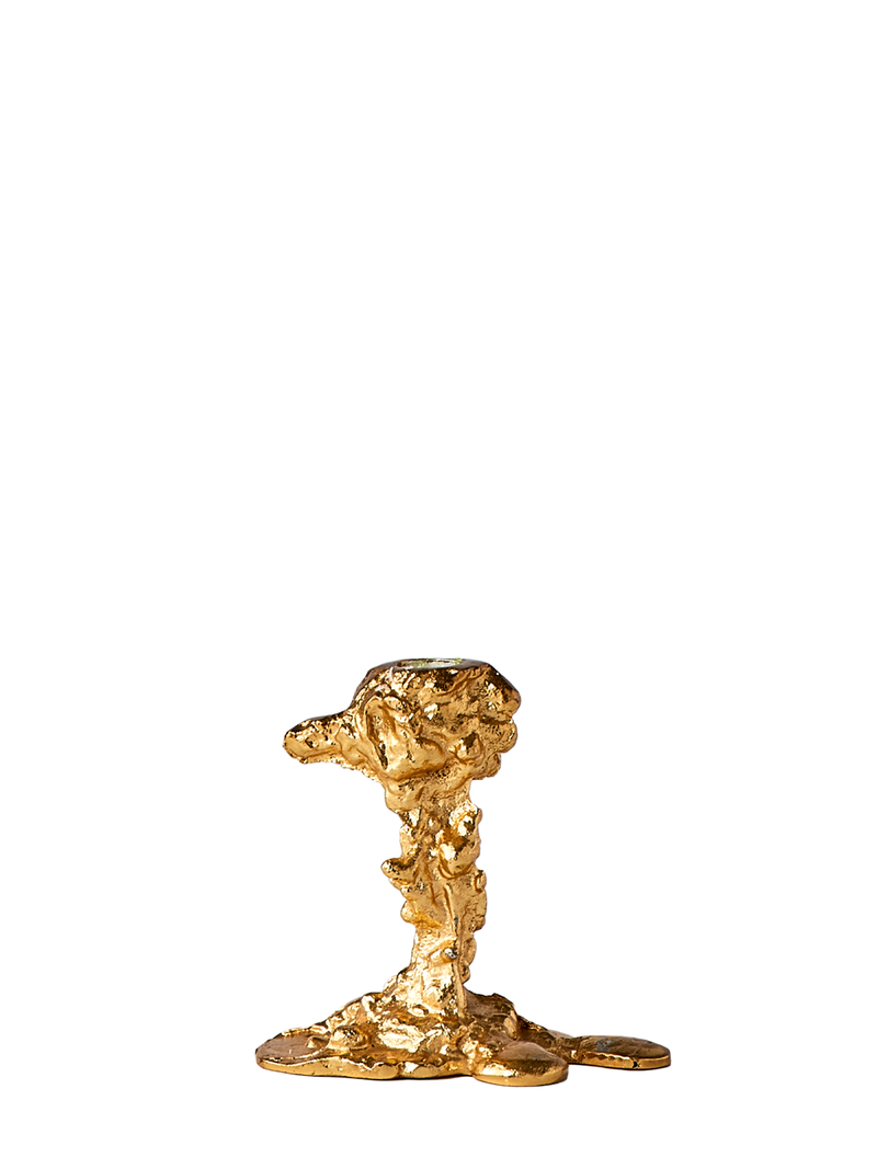 A gold-plated aluminum drip candle holder has an abstract, fluid-like shape on a white background.