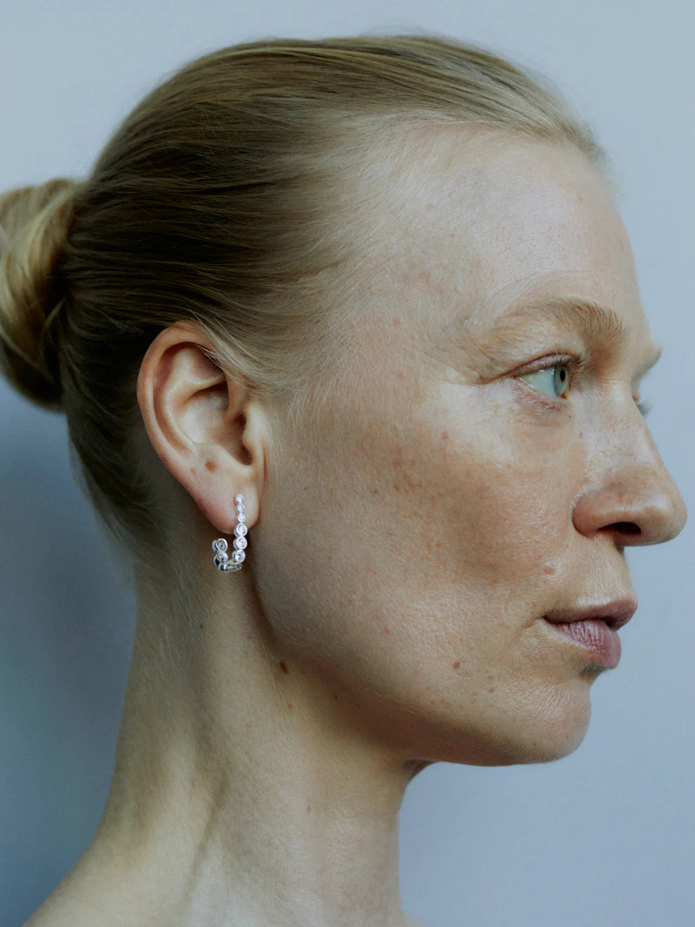 The half-moon circle earrings in sterling silver and crystal clear cuvbc zirconite stones look lovely on the ear of the model with pale Nordic colours on her hair and skin.