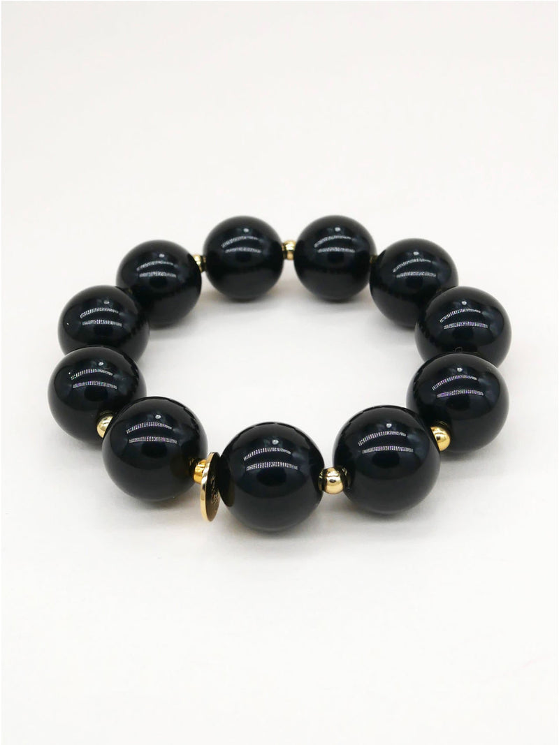 A beaded stretch bracelet featuring glossy black round beads separated by small gold spacer beads, displayed on a clean white background.