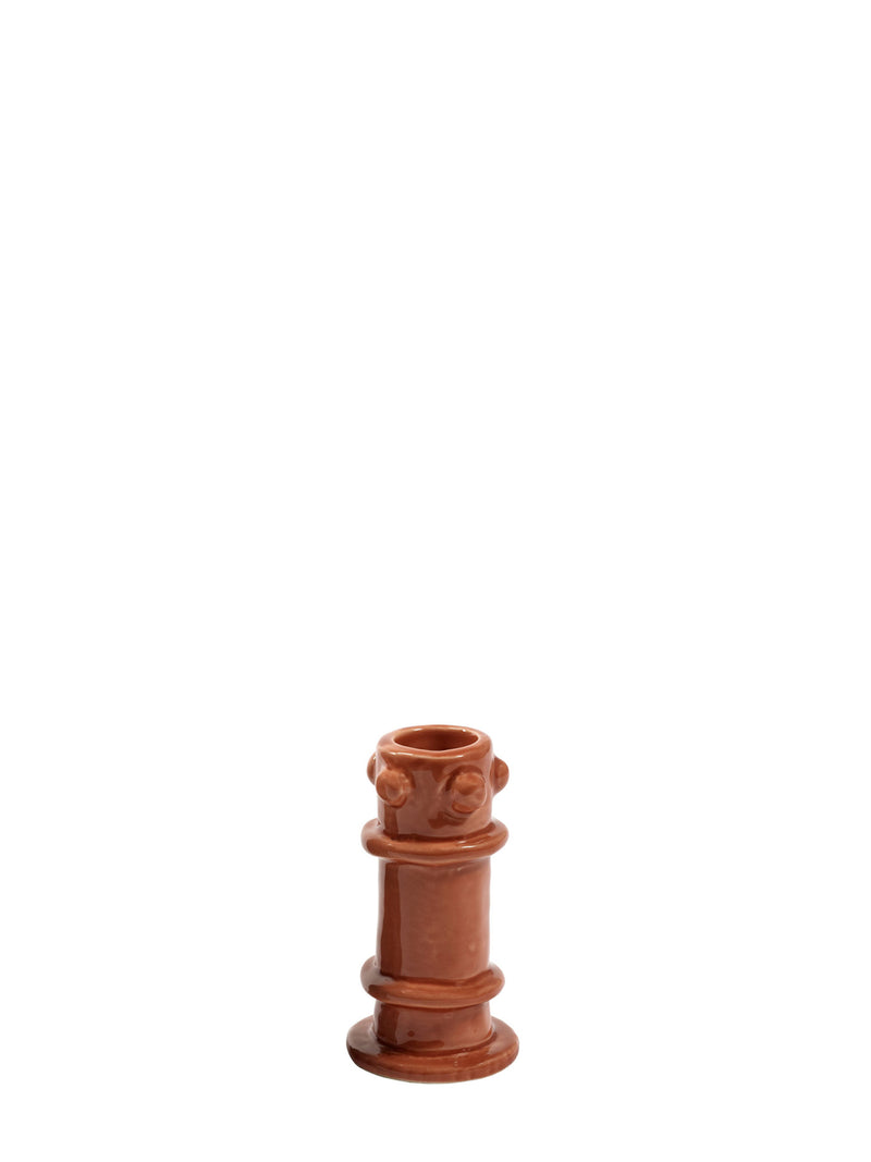 Terracotta candle holder with a face design on a white background