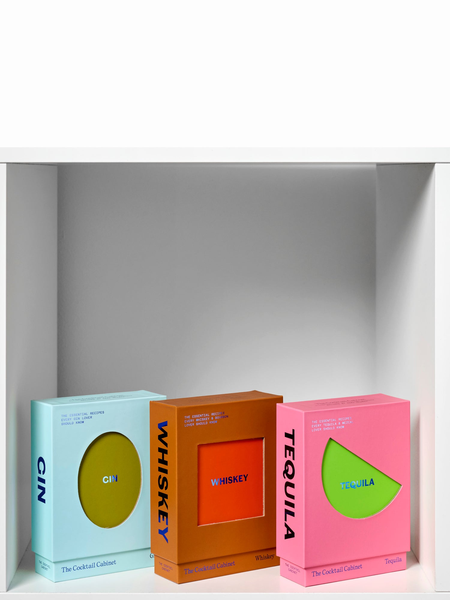 Three colorful boxes labeled 'Gin', 'Whiskey', and 'Tequila' on a white shelf.