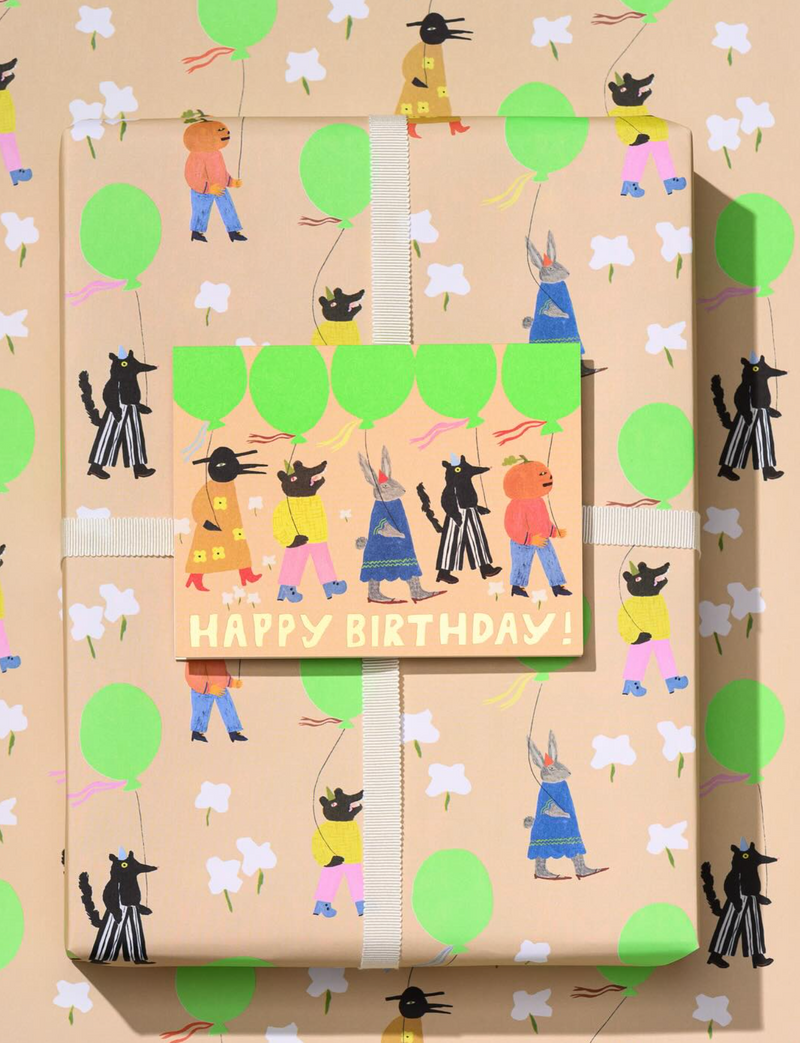 Gift box with 'Happy Birthday!' card featuring cartoon characters and green balloons on a brown background.