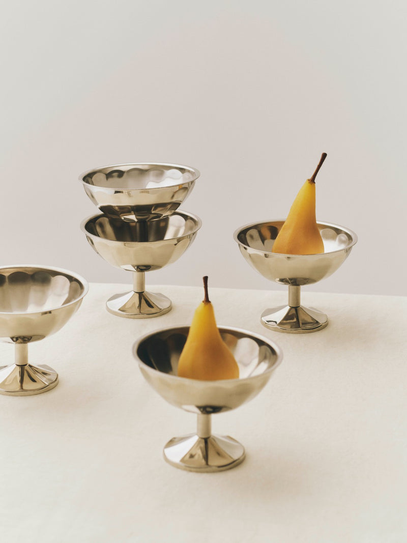Set of metal dessert bowls with pears on a white surface